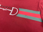 Red T-shirt chest with partial white horsebit graphic and green stripe