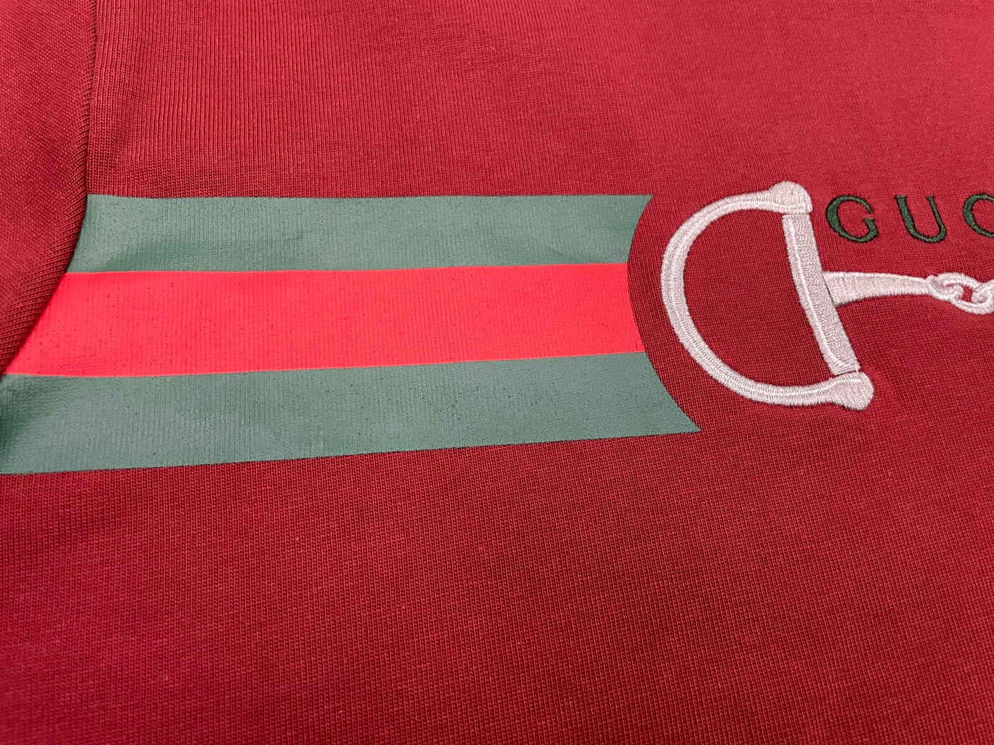 Red T-shirt chest stripe with green and white horsebit logo graphic