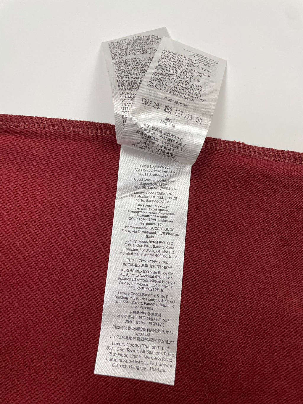 Red T-shirt with stacked white care label tags on the back hem