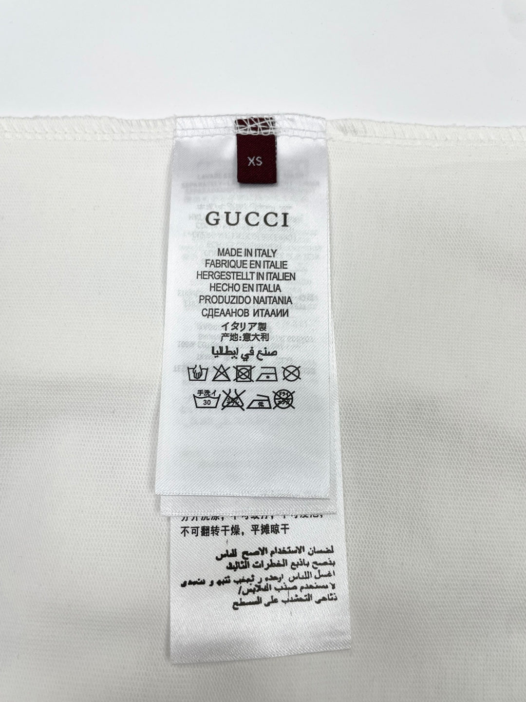White T-shirt size XS label with Gucci and care instructions
