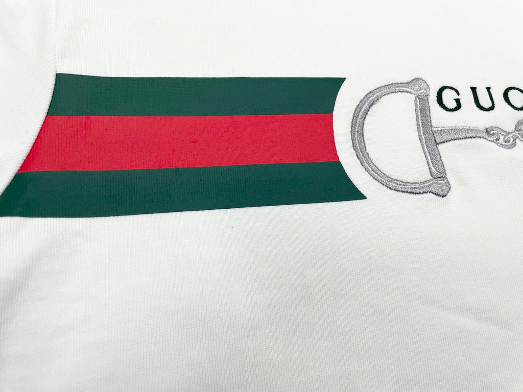 White T-shirt hem with green and red stripe band and horsebit graphic