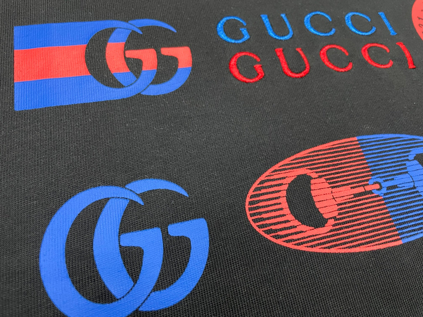 Dark Gucci T-shirt graphic logos and GUCCI lettering in blue and red