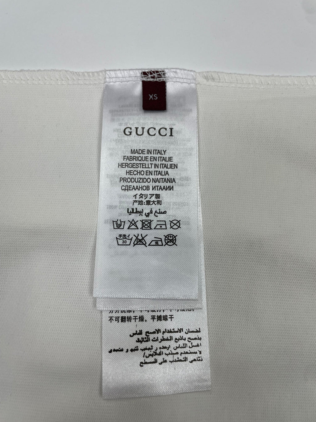 White T-shirt size label marked XS with care icons