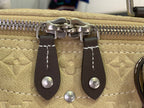 Louis Vuitton bag zipper pull with dark leather tabs and silver hardware on beige canvas