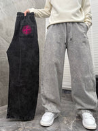 Black denim jogger pants with red logo patch and drawstring waistband