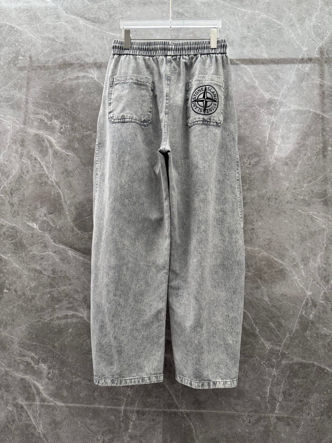 Grey denim jogger pants with stitched pockets and logo patch on right side