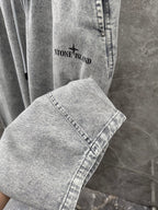 Grey denim jogger pants close-up with logo graphic and stitched cuff