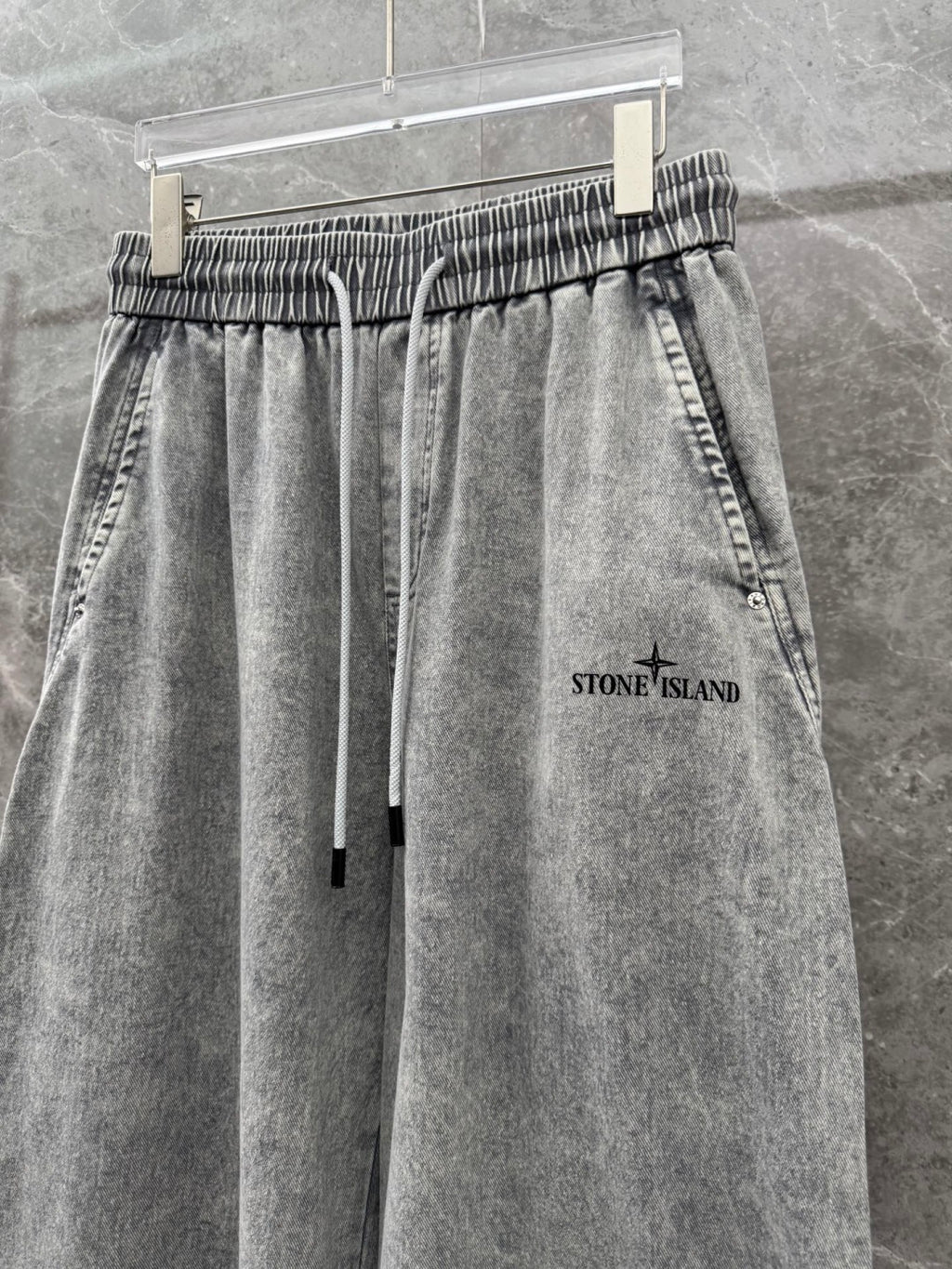 Grey stone-wash denim jogger pants with elastic waist, drawstring, and front pockets