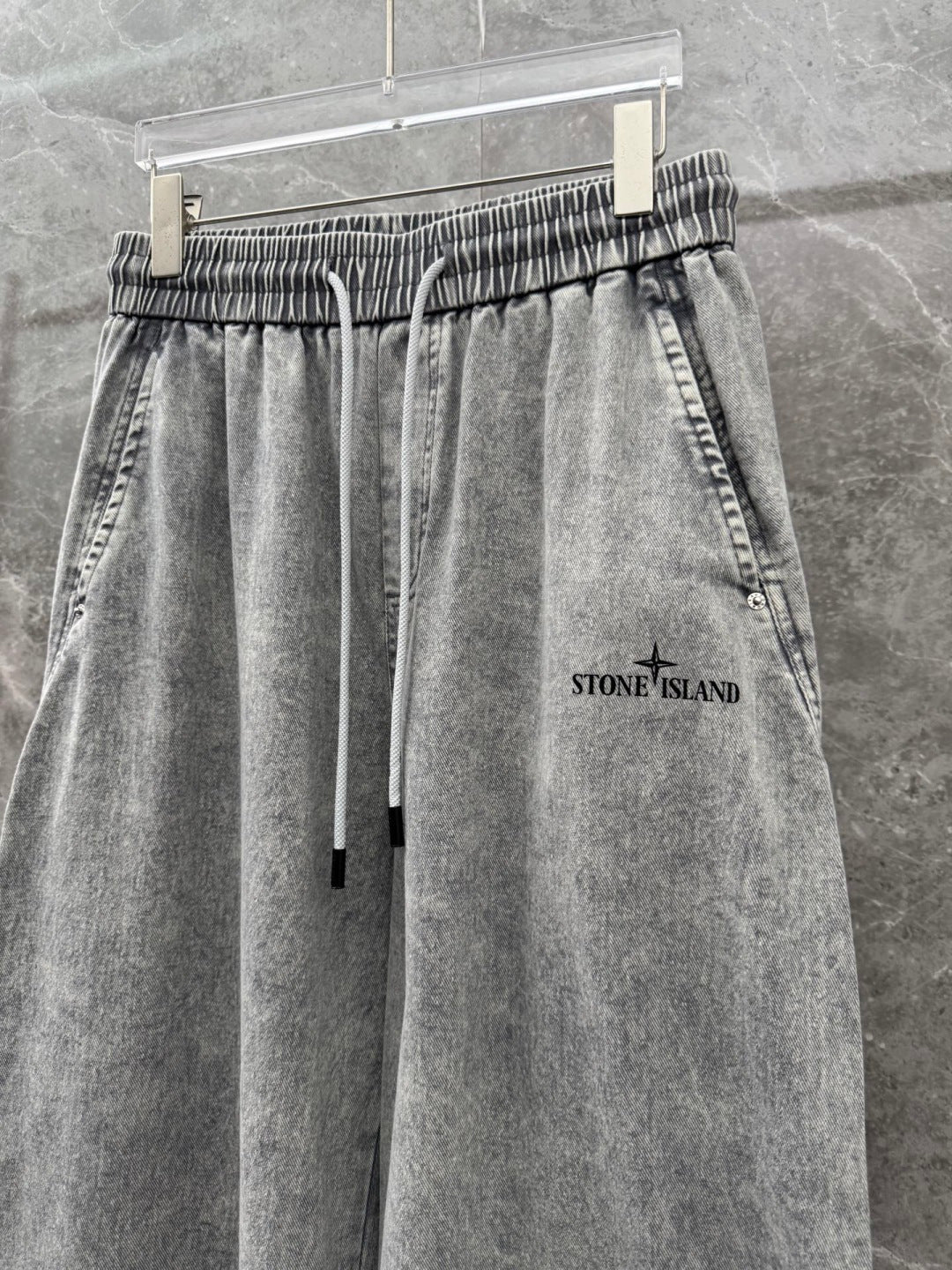 Grey stone-wash denim jogger pants with elastic waist, drawstring, and front pockets