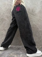 Wide-leg denim pants in dark wash with pink logo patch on side pocket.