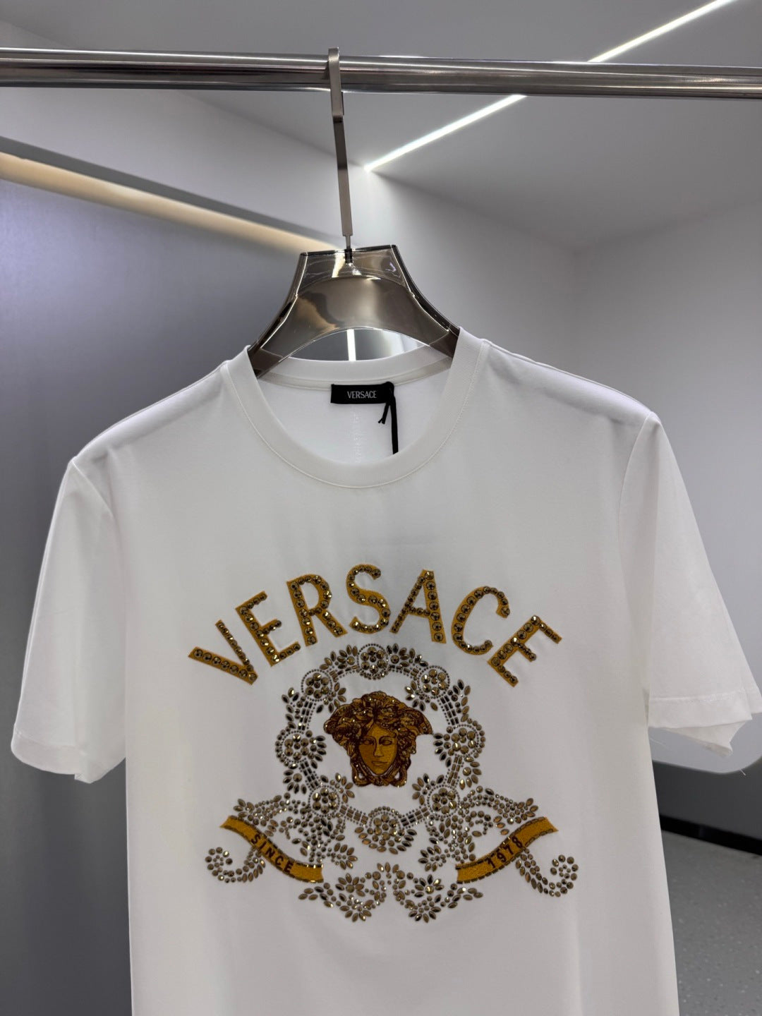 White crew-neck T-shirt with gold VERSACE logo and ornate central graphic