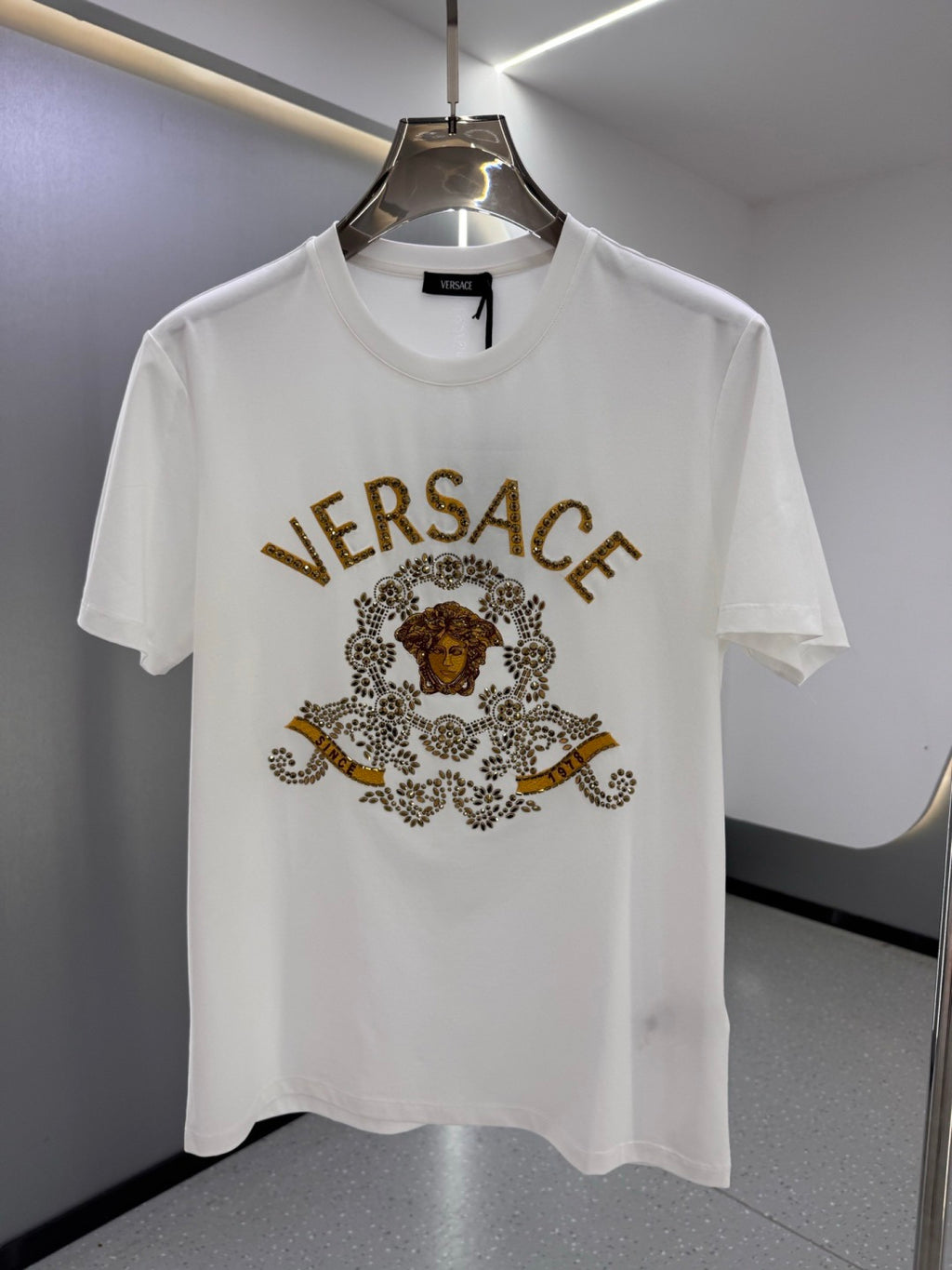 White crew-neck T-shirt with gold VERSACE logo and ornate medallion graphic