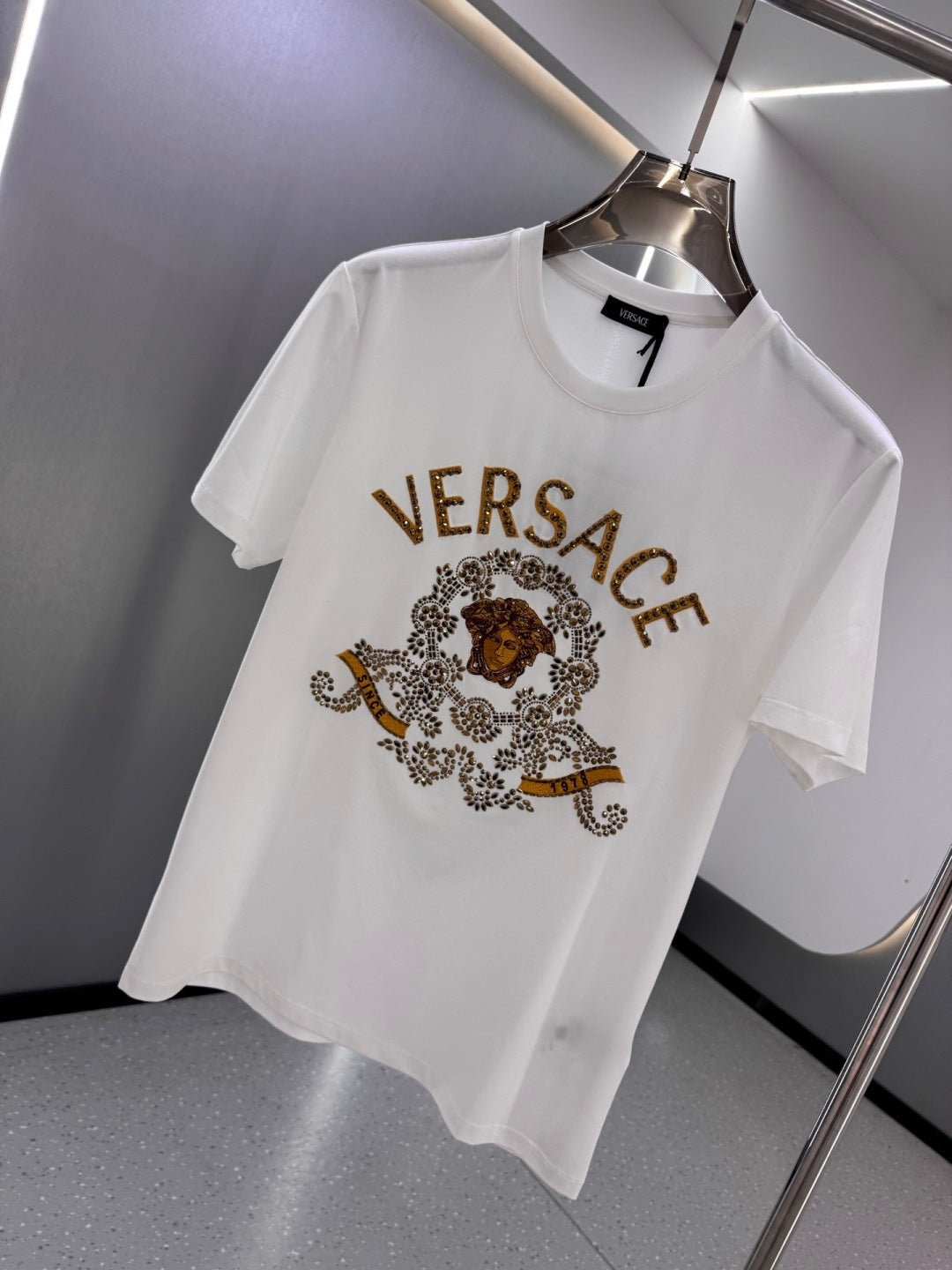 White crew-neck T-shirt with VERSACE text and ornate crest graphic