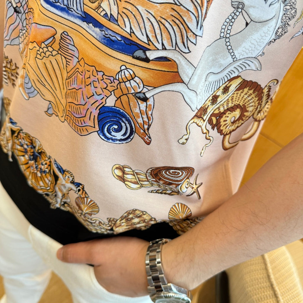 Versace polo shirt close-up of hem: black trim with blue, gold, and seashell print