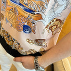 Versace polo shirt close-up of hem: black trim with blue, gold, and seashell print
