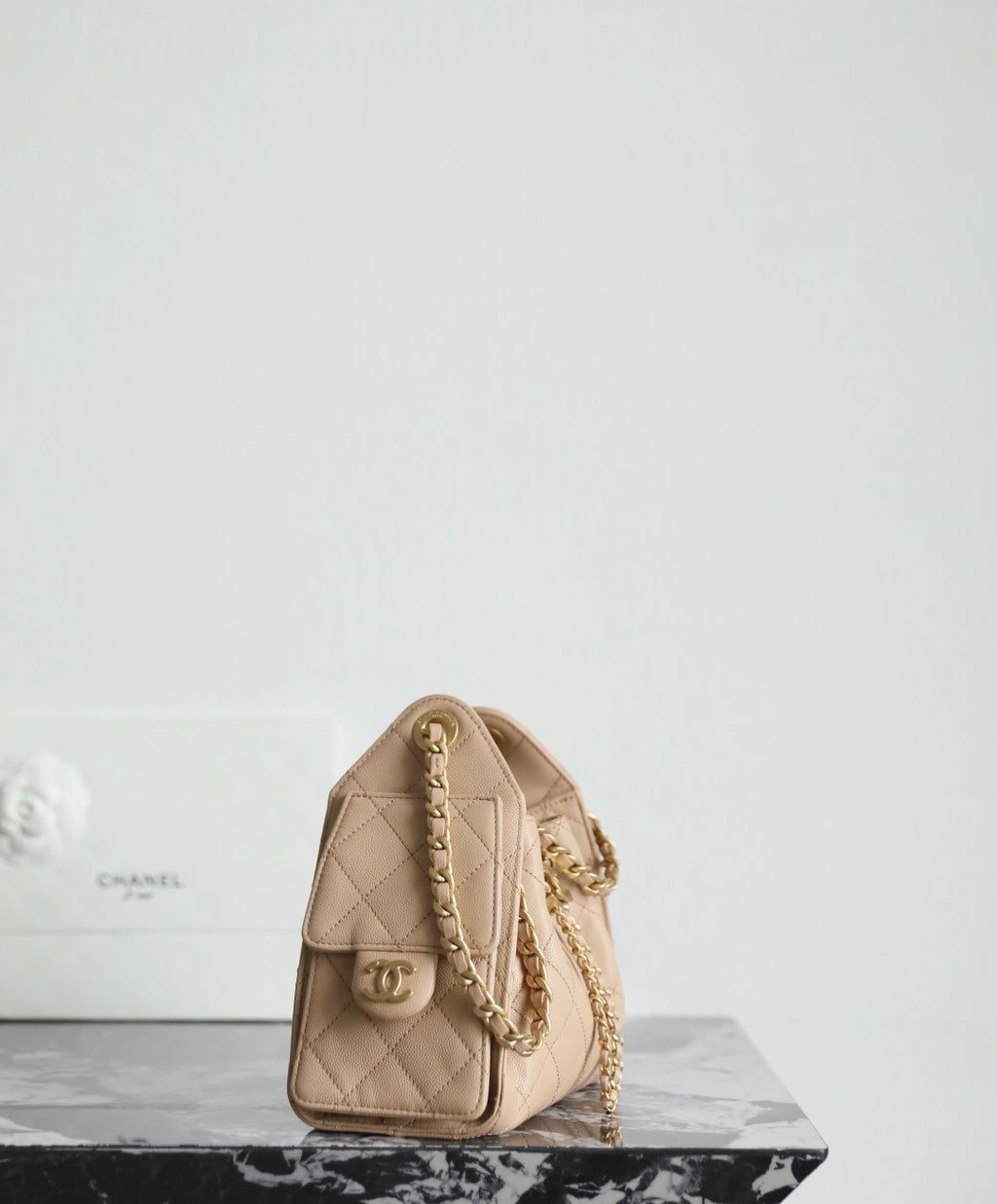 Chanel beige quilted shoulder bag with chain strap and front flap pocket.