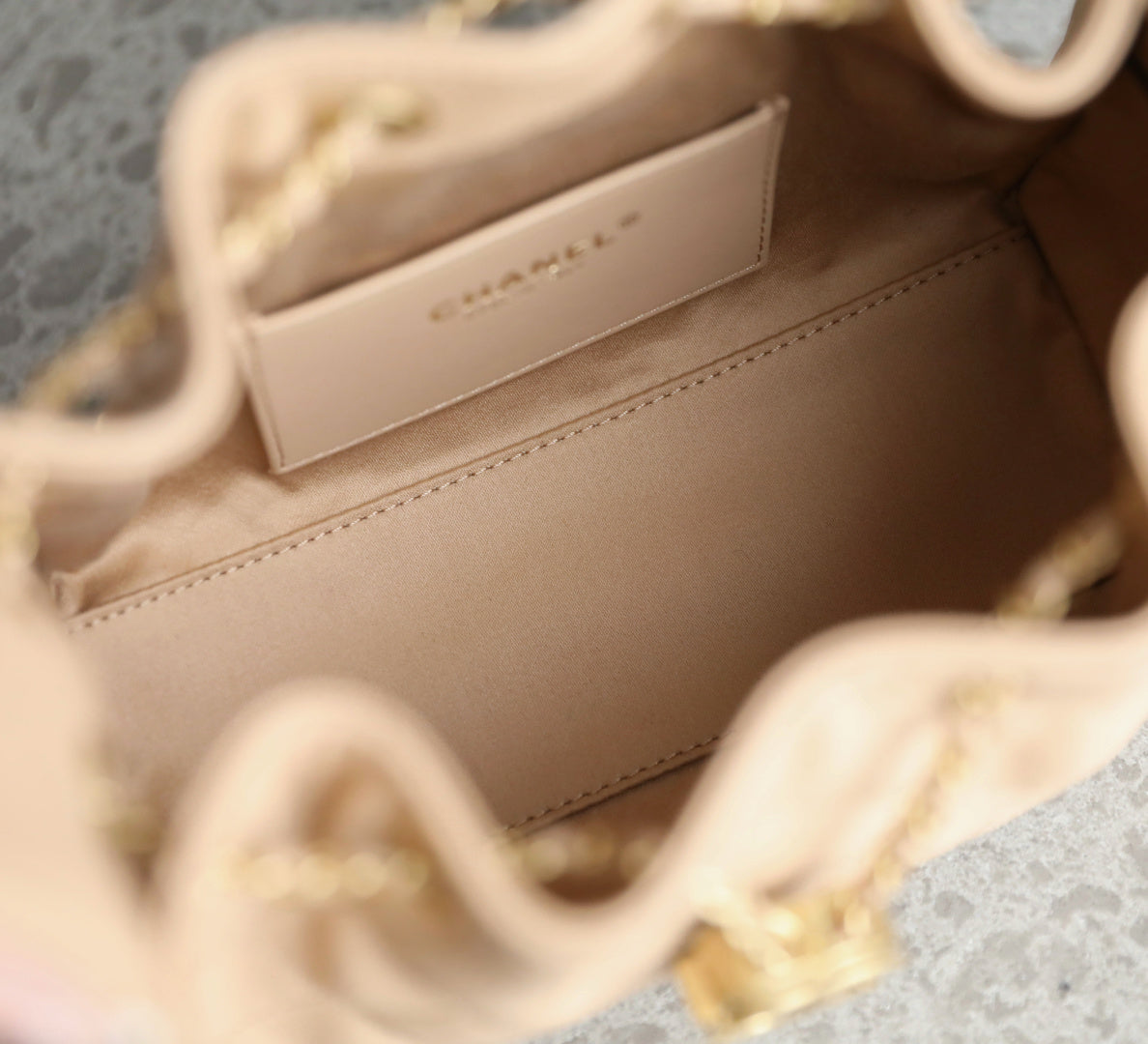 Chanel beige interior lining with stitched panel and gold-tone chain strap hardware.