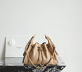 Chanel quilted mini bucket bag in beige with top handle and gold-tone chain straps.