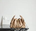 Chanel quilted mini bucket bag in beige with top handle and gold-tone chain straps.