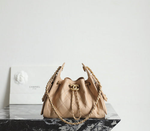 Chanel quilted mini bucket bag in beige with top handle and gold-tone chain straps.