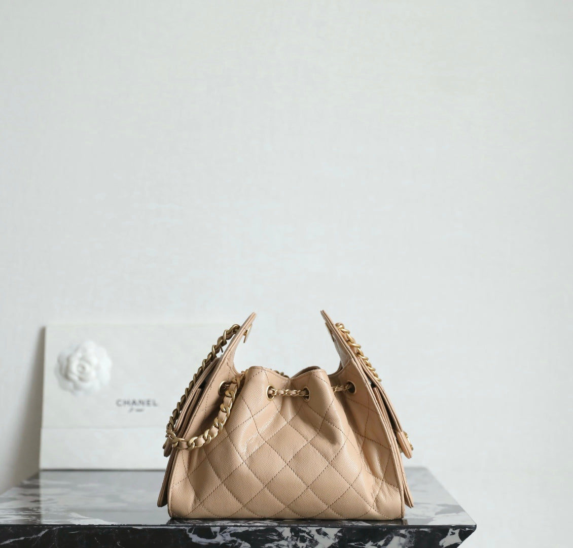 Chanel beige bucket bag with quilted sides, top clasp, and dual chain straps.