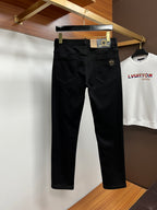 Black pants on hangers, front view with gold logo button and seam lines