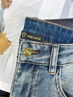 Light-wash denim jeans with gold button, VERSACE waistband text, and belt loops