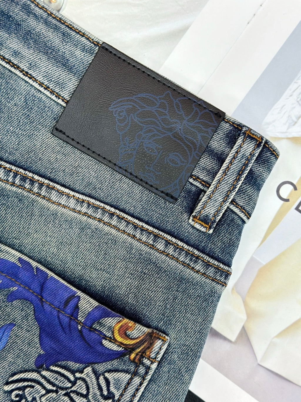 Versace denim jeans waistband with black logo patch and belt loop stitching