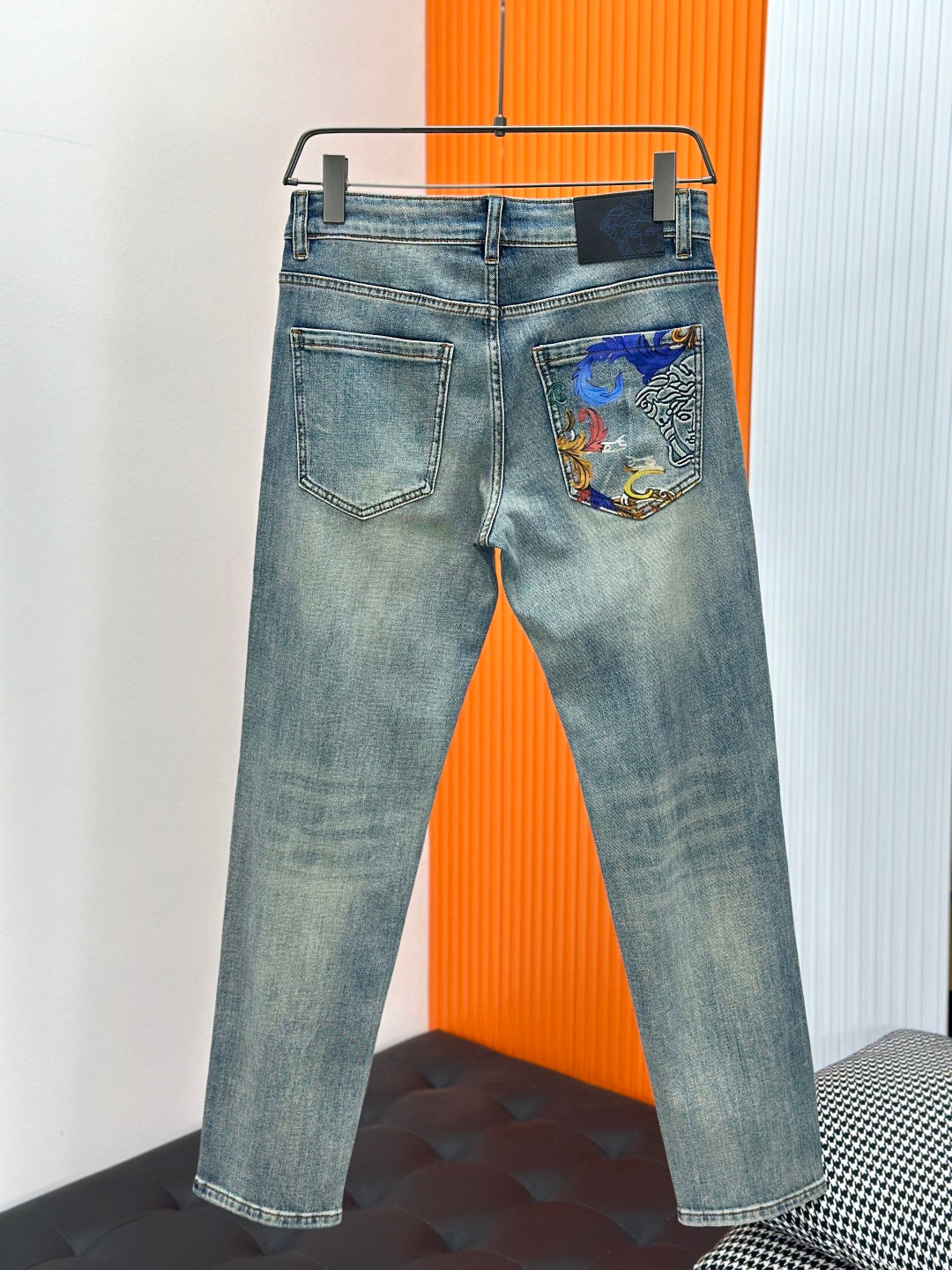 Light-wash denim jeans with stitched pockets and colorful graphic panel on right back pocket
