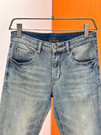 Light-wash denim jeans with VERSACE waistband logo, belt loops, and button closure