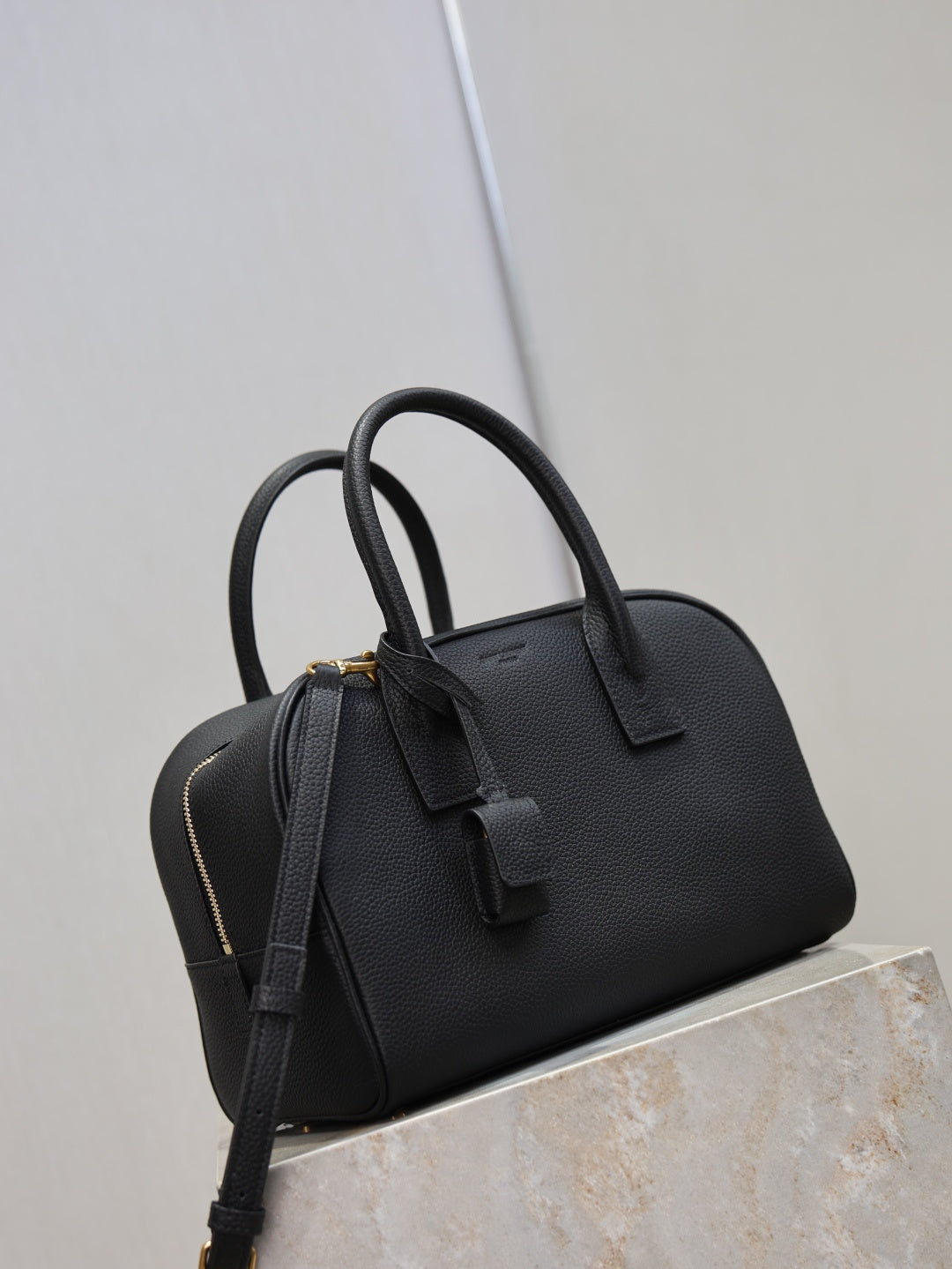 Black structured handbag with double top handles and crossbody strap