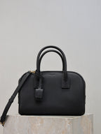 Black structured handbag with top handles, front strap detail, and crossbody strap