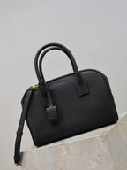 Black structured handbag with top handle, front strap detail, and adjustable shoulder strap