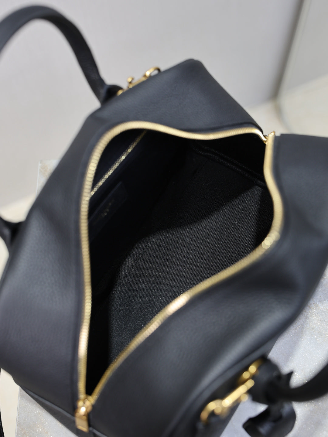 Black handbag interior with gold-trimmed zipper opening