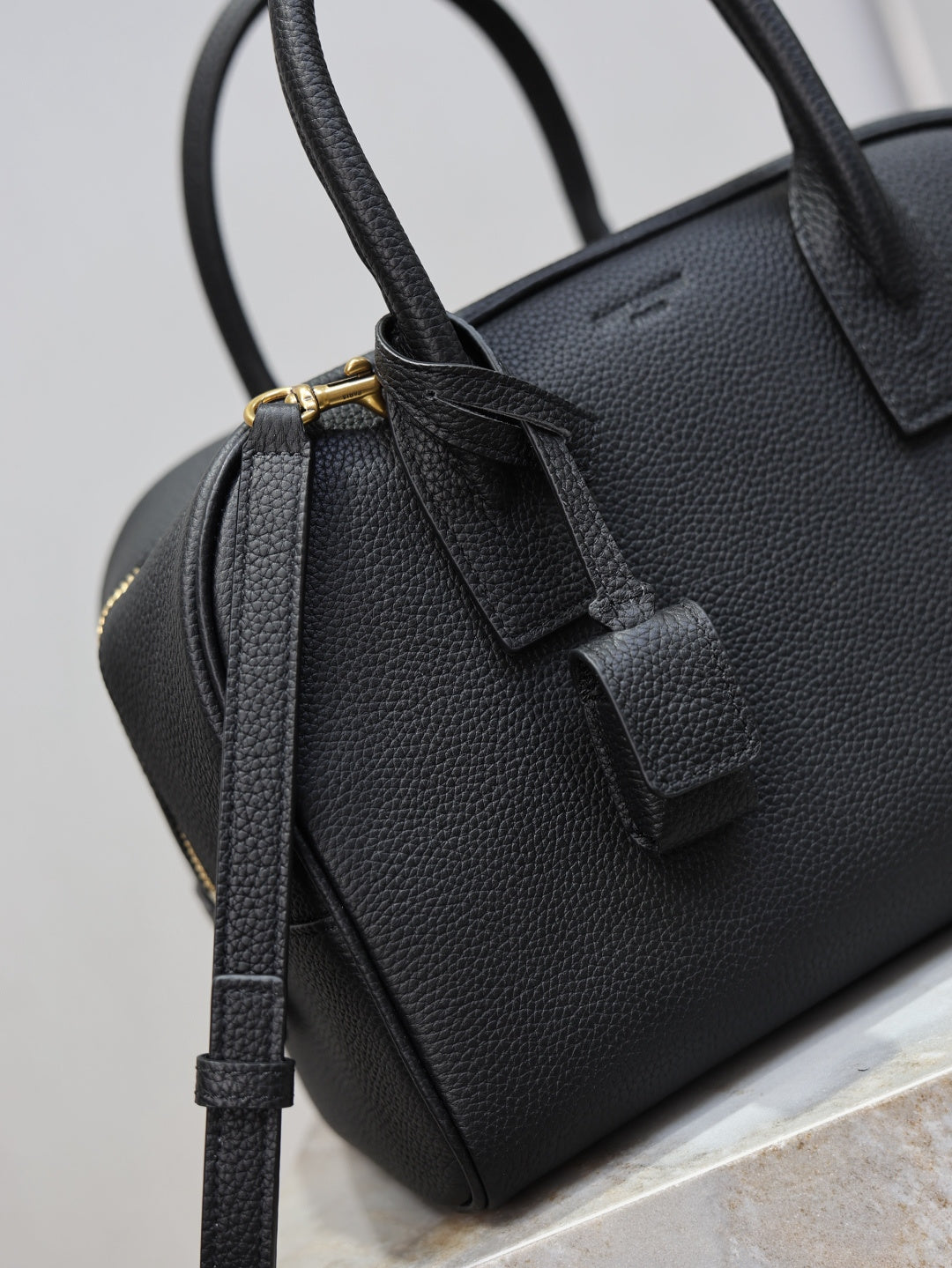 Black pebbled leather handbag with front strap tab and gold-tone hardware