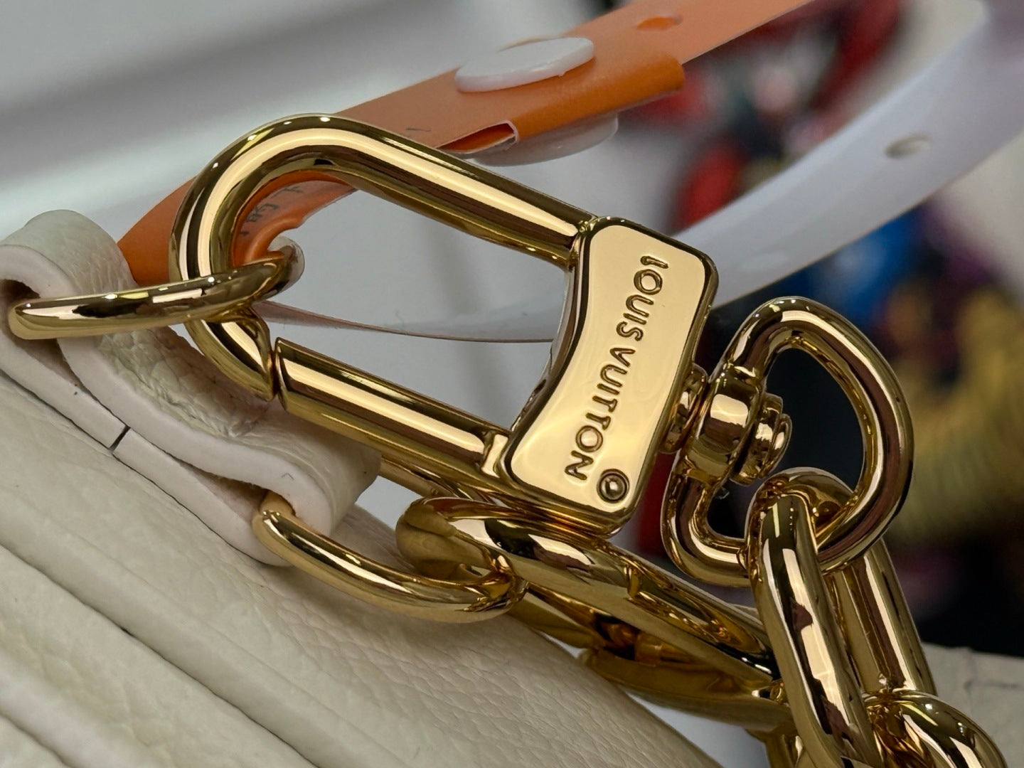 Louis Vuitton gold-tone clasp and D-ring on cream leather strap with chain attachment