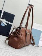 Brown Prada bucket-style bag with drawstring closure, top handles, and side strap