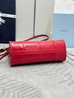 Red leather barrel-style handbag with top handle and shoulder strap, gold-tone hardware