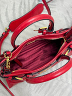 Red leather handbag interior with zipper, textured lining, and gold-tone hardware