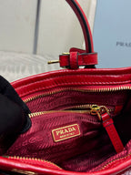 Red leather handbag interior with logo patch and zipper pull, showing textured lining