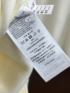 Off-white knit sweater care label tag on inside neckline.