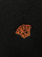 Orange embroidered logo on a black knit sweater chest