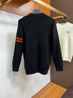 Black knit sweater with orange striped sleeve detail and small orange back logo