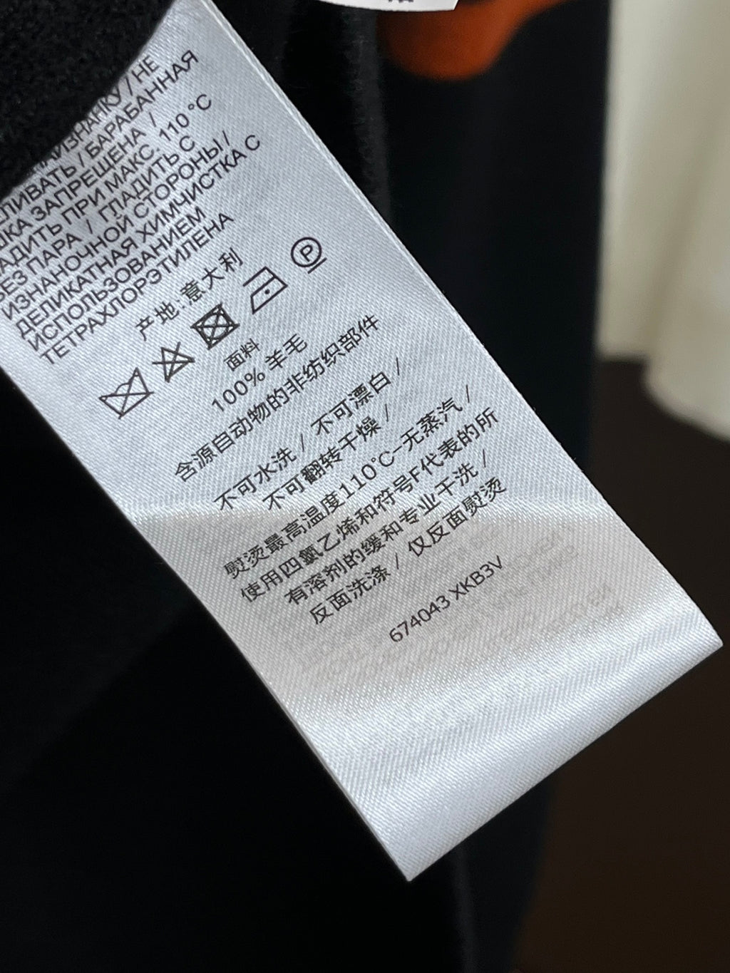 Black knit sweater care label on fabric with washing symbols