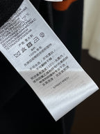 Black knit sweater care label on fabric with washing symbols