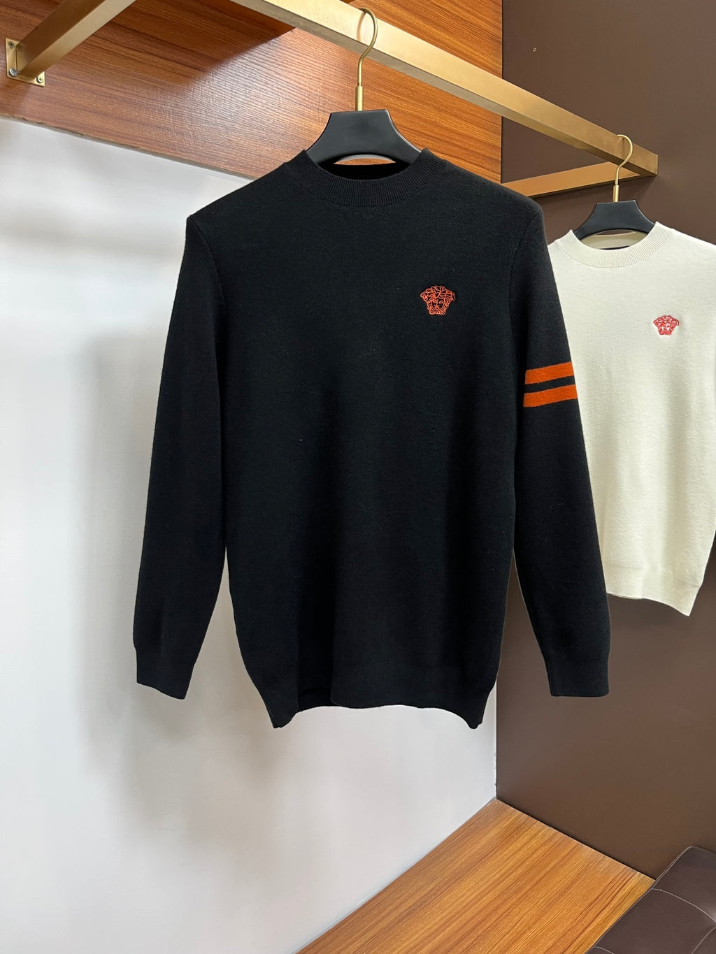 Black knit sweater with small orange embroidered logo on the chest