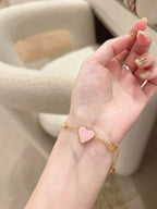 Gold heart charm bracelet on wrist, pink heart pendant with dangling links