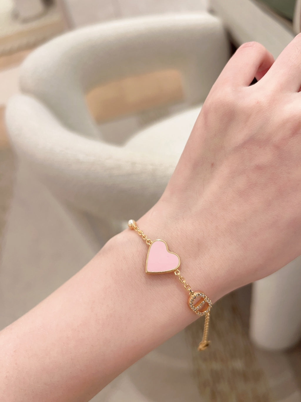 Heart charm bracelet on wrist with pink enamel heart and gold link accents