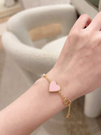 Heart charm bracelet on wrist with pink enamel heart and gold link accents