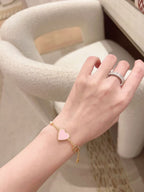 Heart charm bracelet on wrist, pink heart enamel and gold-tone chain